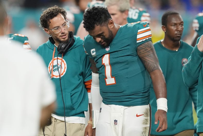 El entrenador en jefe de los Dolphins de Miami, Mike McDaniel, habla con el mariscal de campo Tua Tagovailoa (1) mientras abandona el juego después de sufrir una conmoción cerebral durante la segunda mitad de un partido contra los Bills de Buffalo , el jueves 12 de septiembre de 2024, en Miami Gardens, Florida (AP Foto/Rebecca Blackwell)