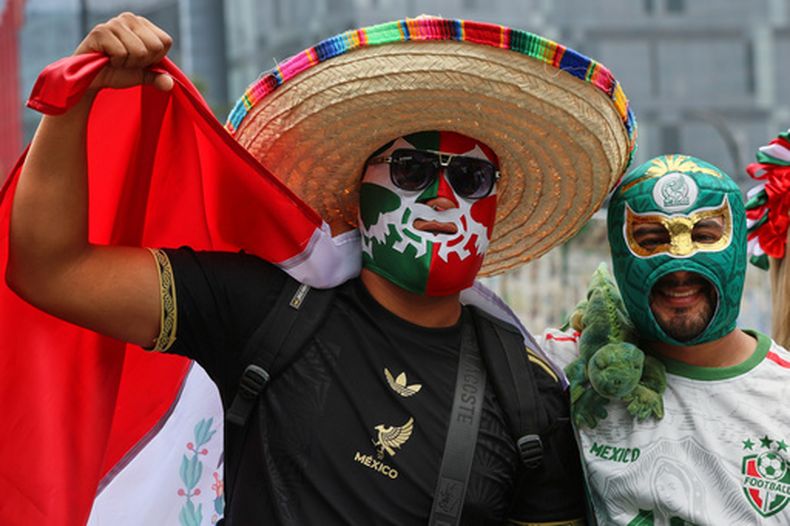 Aficionados mexicanos con máscaras llegan a una fiesta cerca del Ángel de la Independencia en la capital de su país, el domingo 5 de julio de 2026 (AP Foto/Ginnette Riquelme)