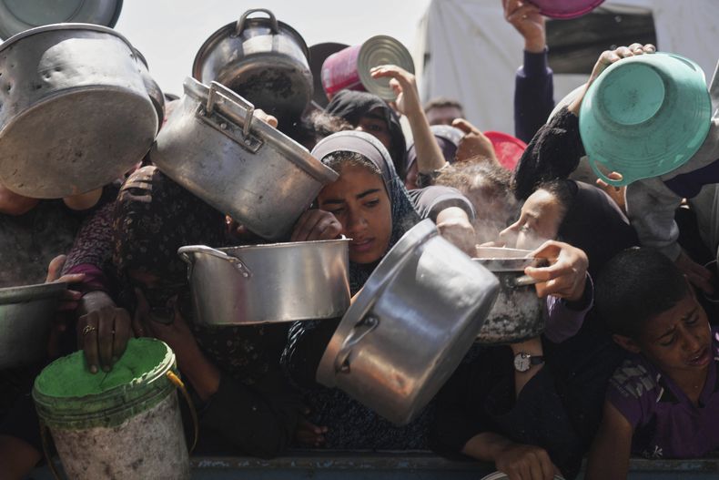 Palestinos intentan conseguir comida donada en una cocina comunitaria, el lunes 5 de mayo de 2025, en Jan Yunis, Franja de Gaza. (AP Foto/Abdel Kareem Hana)