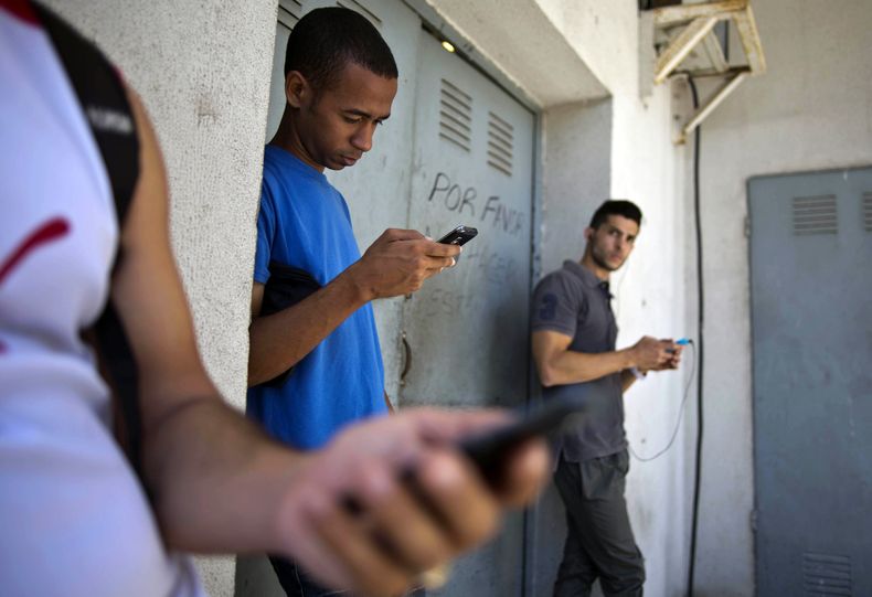 Estudiantes reunidos detr&aacute;s de un negocio intentan encontrar una se&ntilde;al de internet para sus tel&eacute;fonos multifuncionales en La Habana, Cuba, el 1 de abril de 2014. El gobierno de Costa Rica dice que aguarda una explicaci&oacute;n de Est
