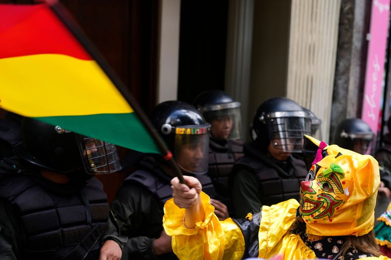 Un manifestante vestido como el personaje de carnaval Pepino sostiene una bandera boliviana frente a la embajada peruana para protestar contra el uso de este personaje por parte de Perú y su apropiación cultural en La Paz, Bolivia, el lunes 17 de noviembre de 2025. (Foto AP/Juan Karita).