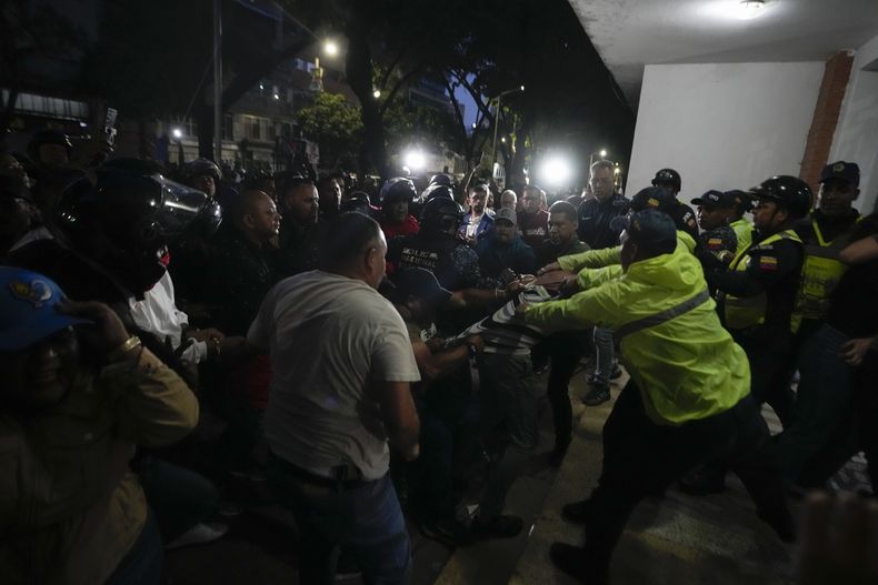 Simpatizantes del gobierno agarran a un partidario de la oposición mientras oficiales de la policía intervienen durante la elección presidencial en Caracas, Venezuela, el sábado 28 de julio de 2024. (AP Foto/Matías Delacroix)