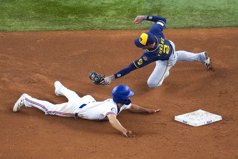 Josh Smith, abajo, de los Rangers de Texas, se roba segunda base superando el tiro e intento de toque por parte de Brice Turang, segunda base de los Cerveceros de Milwaukee, durante la quinta entrada del juego de béisbol de Grandes Ligas del miércoles 10 de septiembre de 2025, en Arlington, Texas. (AP Foto/Julio Cortez)