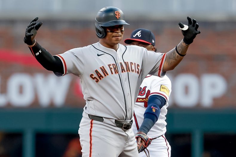 El bateador designado de los Gigantes de San Francisco, Rafael Devers (izquierda), reacciona tras conectar un doblete productor de una carrera mientras el segunda base de los Bravos de Atlanta, Ozzie Albies (atrás), observa durante la primera entrada de un partido de béisbol, el miércoles 17 de junio de 2026, en Atlanta. (Foto AP/Erik S. Lesser)
