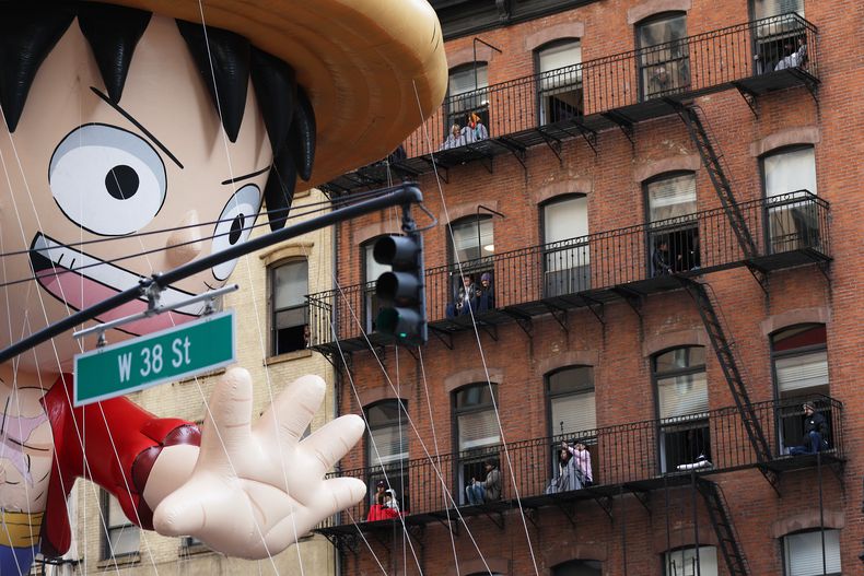 Gente observa desde sus balcones cómo el globo de Monkey D. Luffy pasa junto a ellos durante el Desfile del Día de Acción de Gracias de Macys, el jueves 27 de noviembre de 2025, en Nueva York. (Foto AP/Heather Khalifa)