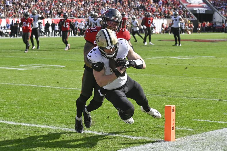 Taysom Hill (7), tight end, de los Saints de Nueva Orleans, anota un touchdown después de recibir un pase, con el intento del safety Antoine Winfield Jr. (31), de los Buccaneers de Tampa Bay, en la primera mitad del juego de la NFL, el domingo 31 de diciembre de 2023. (AP Foto/Jason Behnken)