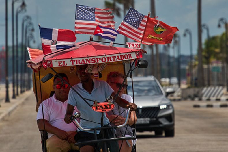 Pasajeros viajan en un bicitaxi adornado con las banderas de Estados Unidos, Cuba y la República Dominicana, el miércoles 20 de mayo de 2026, en La Habana, Cuba. (AP Foto/Ramón Espinosa)