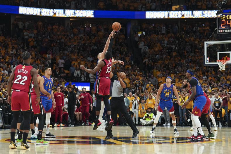 Bam Adebayo (13), del Heat de Miami, y Nikola Jokic, de los Nuggets de Denver, detrás, brincan en el arranque del Juego 1 de las Finales de la NBA, el jueves 1 de junio de 2023, en Denver. (AP Foto/Jack Dempsey)