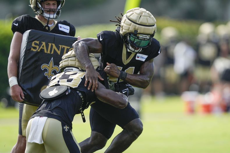 En foto del primero de agosto del 2023, el corredor de los Saints de Nueva Orleans Alvin Kamara realiza un ejercicio frente al receptor Kirk Merritt. El viernes 4 de agosto del 2023, Kamara es suspendido tres juegos por altercado que involucró al defensive back de los Colts. Chris Lammons. (AP Foto/Gerald Herbert)