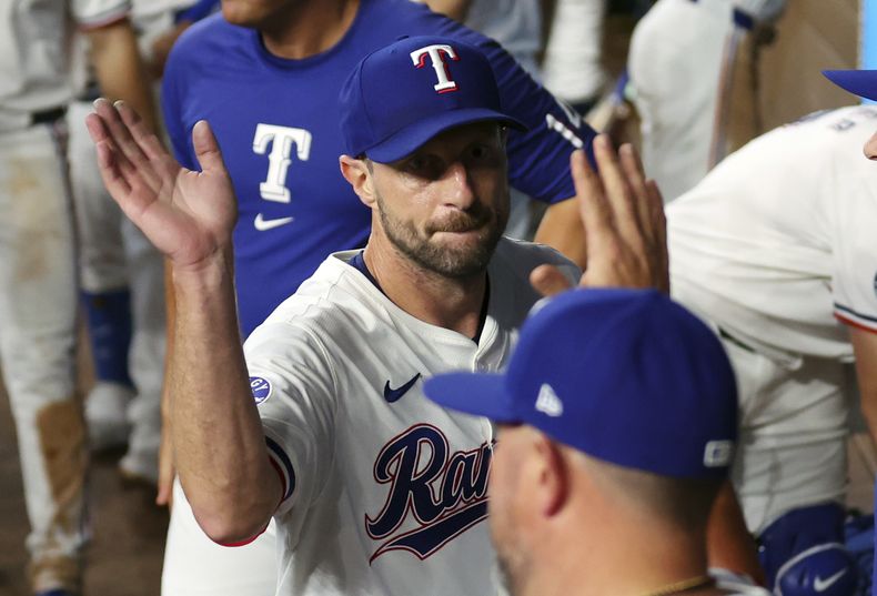 El abridor de los Rangers de Texas, Max Scherzer (centro) es felicitado en el banco luego de lanzar en el sexto episodio del juego ante los Medias Blancas de Chicago, el jueves 25 de julio de 2024, en Arlington, Texas. (AP Foto/Richard W. Rodriguez)
