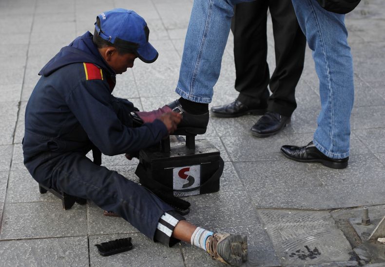 Lucas, de 13 a&ntilde;os, lustra zapatos en una calle de La Paz, Bolivia, el 7 de julio del 2014. Mientras que en el resto del mundo se combate el trabajo infantil, en Bolivia se aprob&oacute; una ley que lo legaliza a partir de los 10 a&ntilde;os. (AP Ph