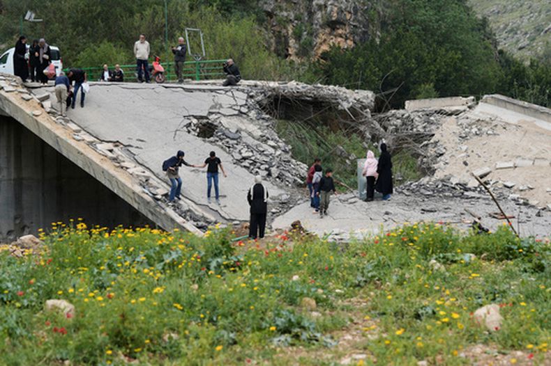 Personas desplazadas cruzan a pie un puente destruido para regresar a sus pueblos tras un cese el fuego entre Hezbollah e Israel, en el poblado de Tayr Felsay, cerca de la ciudad de Tiro, en el sur de Líbano , el domingo 19 de abril de 2026. (AP Foto/Bilal Hussein)