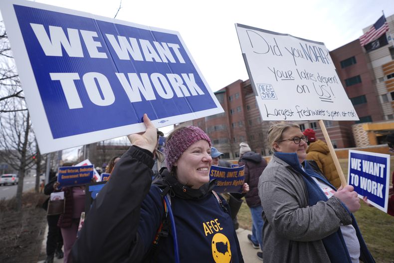 Katy Frank (izquierda), exinformática del Laboratorio de Investigación Ambiental de los Grandes Lagos de NOAA, que fue despedida, protesta en el exterior del centro médico para veteranos John D. Dingell, en Detroit, el 28 de febrero de 2025. (AP Foto/Paul Sancya)