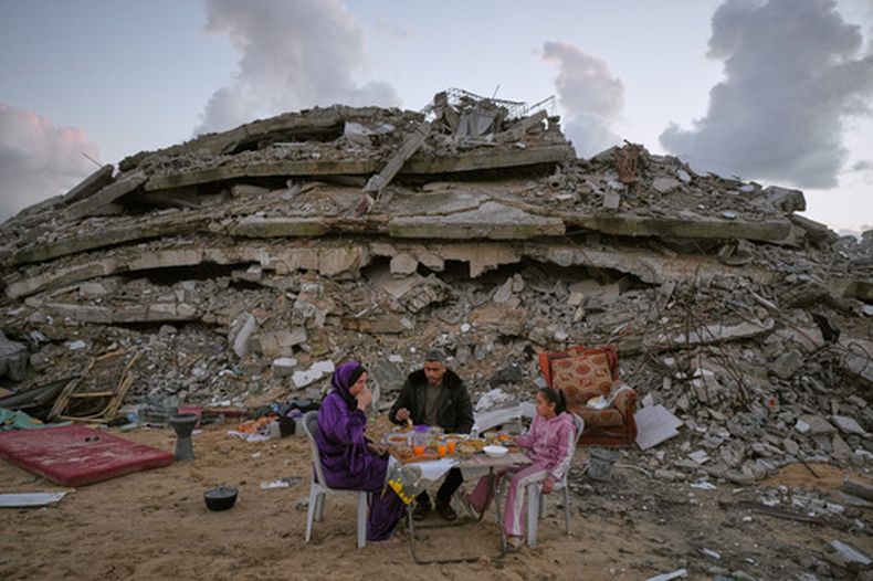 Heba al-Yazji, su esposo, Saddam, y su hija, Maryam, rompen el ayuno durante el mes sagrado musulmán de ramadán, en medio de los escombros de edificios destruidos en la Ciudad de Gaza, el martes 24 de febrero de 2026. (AP Foto/Jehad Alshrafi)