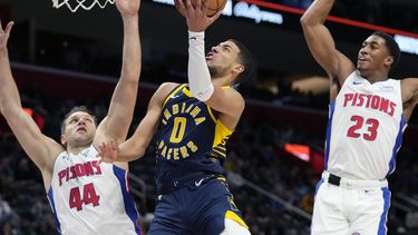 Tyrese Haliburton (0), de los Pacers de Indiana, intenta una bandeja ante la presión defensiva de Bojan Bogdanovic (44) y Jaden Ivey (23) durante la primera mitad del juego de baloncesto de la NBA, el lunes 11 de diciembre de 2023, en Detroit. (AP Foto/Carlos Osorio)