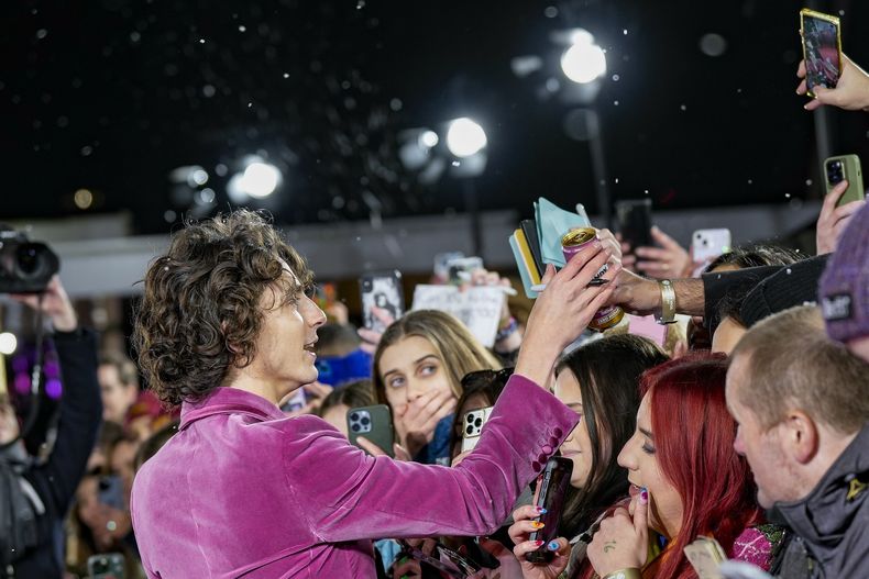 Timothee Chalamet recibe una bebida de un fan a su llegada a la premiere mundial de Wonka el martes 28 de noviembre de 2023 en Londres. (Scott Garfitt/Invision/AP)