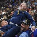Michael Malone, entrenador de los Nuggets de Denver, es levantado por un grupo de fanáticos tras coronarse en las Finales de la NBA ante el Heat de Miami, el lunes 12 de junio de 2023