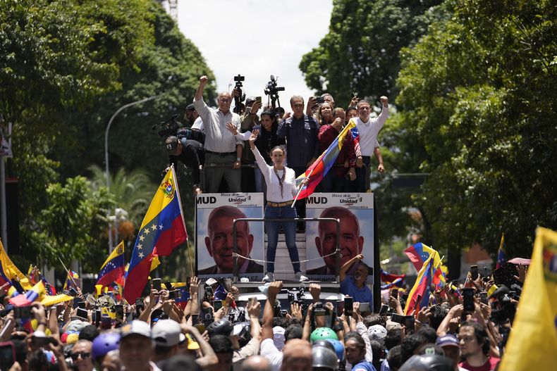 La líder opositora María Corina Machado sostiene una bandera nacional mientras saluda a sus partidarios a su llegada a un mitin en Caracas, Venezuela, el sábado 3 de agosto de 2024. (AP Foto/Matías Delacroix)
