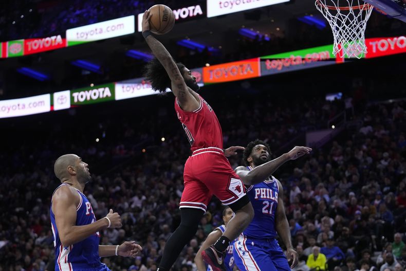 Coby White, de los Bulls de Chicago, realiza una clavada frente a Joel Embiid (derecha), de los 76ers de Filadelfia, el lunes 18 de diciembre de 2023 (AP Foto/Matt Slocum)