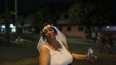 Elisheva Rose, que se viste de novia para ayudar a llevar clientes al puesto de tamales de su esposo, es sorprendida por la cámara con una bebida energética en la mano, en Durán, una ciudad ubicada frente a Guayaquil, Ecuador, el 2y de septiembre de 2023. Esta maestra de Inglés y Arte natural de Sudáfrica contó que se mudó a Ecuador porque su esposo es ecuatoriano-israelí, pero ahora quieren mudarse de país por el aumento de la delincuencia. (AP Foto/Rodrigo Abd)