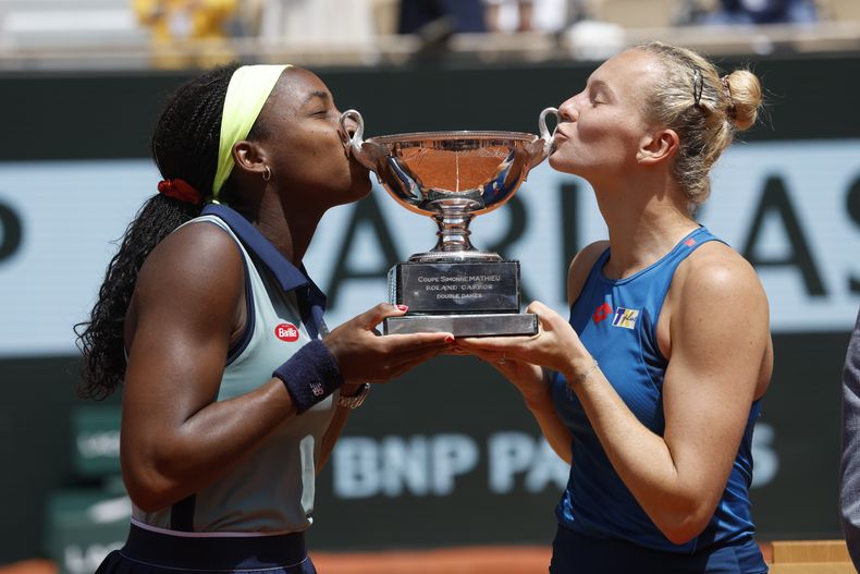 La estadounidense Coco Gauff y la checa Katerina Siniakova le dan un beso al trofeo tras ganar el dobles femenino del Abierto de Francia al superar a las italianas Sara Errani y Jasmine Paolini el domingo 9 de junio del 2024.. (AP Foto/Jean-Francois Badias)