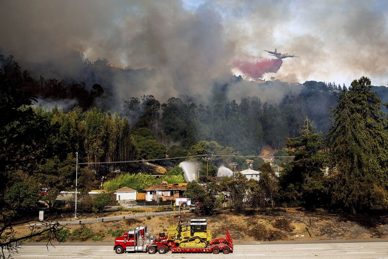 Una aeronave arroja retardante de fuego sobre un incendio que arde cerca de la carretera interestatal 580, el viernes 18 de octubre de 2024, en Oakland, California. (AP Foto/Noah Berger)