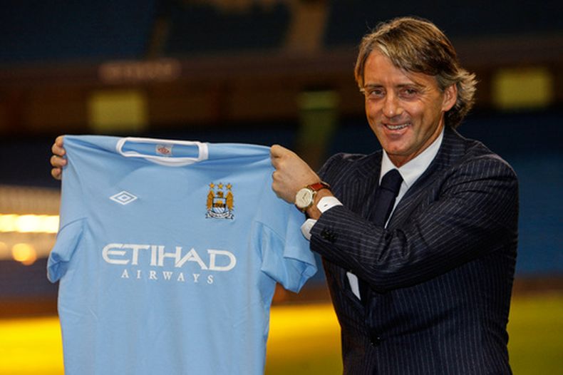 ARCHIVO - El técnico Robert Mancini alza una camiseta del Manchester City, el 21 de diciembre de 2009. (AP Foto/Jon Super)