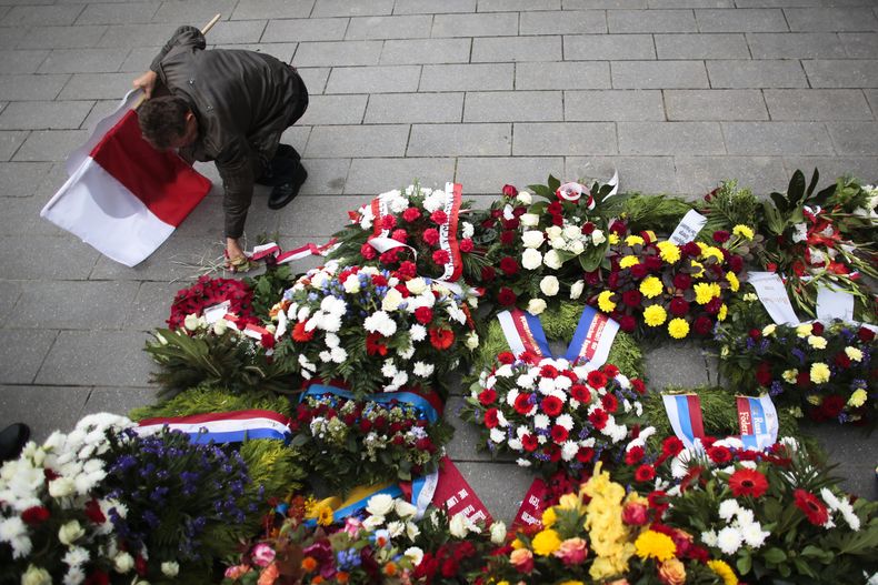 ARCHIVO - Un hombre con una bandera polaca coloca flores luego de una ceremonia para conmemorar la invasión nazi en Polonia, al inicio de la Segunda Guerra Mundial hace 75 años, en Berlín, el 1 de septiembre de 2014. (AP Foto/Markus Schreiber, Archivo)