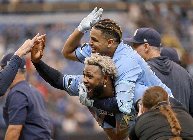 El dominicano de los Rays de Tampa Bay, Junior Caminero (centro debajo) y su compatriota Christopher Morel (centro superior) celebran luego del triunfo en 12 episodios sobre los Arizona Diamondbacks, el domingo 18 de agosto de 2024, en San Petersburgo, Florida. (AP Foto/Jason Behnken)