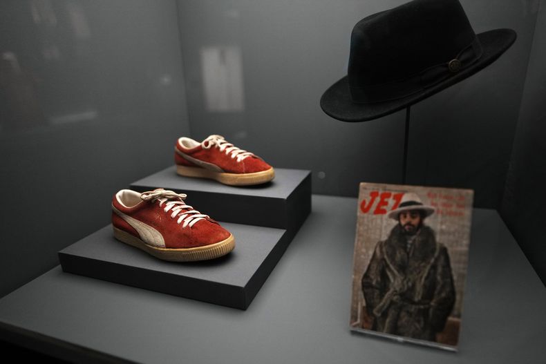 Unas zapatillas PUMA y un sombrero usado por Walt Frazier se exhiben en la exposición del Instituto del Vestido del Museo Metropolitano de Arte, Superfine: Tailoring Black Style, el sábado 3 de mayo de 2025, en Nueva York. (Foto Charles Sykes/Invision/AP)