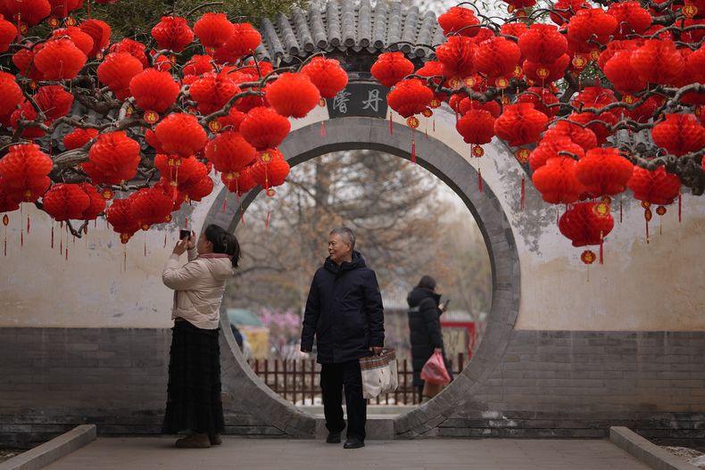 ARCHIVO - residentes se toman una fotografía en un árbol decorado con linterna rojas antes del año nuevo lunar chino en el Parque Ditan en Beijing, el domingo 4 de febrero de 2024. (Foto AP/Andy Wong, archivo)
