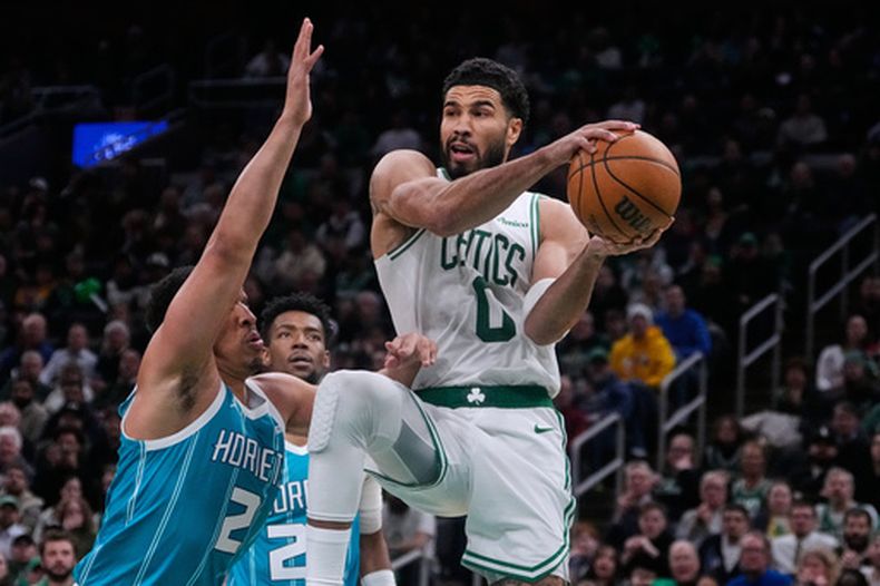 El alero de los Celtics de Boston Jayson Tatum observa antes de pasar el balón mientras lo defiende el alero de los Hornets de Charlotte Grant Williams en el encuentro del martes 7 de abril del 2026. (AP Foto/Charles Krupa)