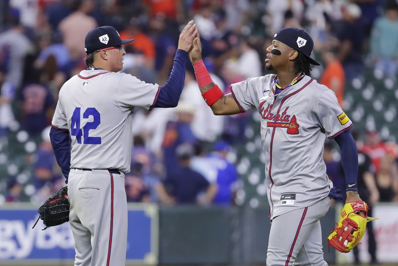 El lanzador de los Bravos de Atlanta, Jesse Chávez, a la izquierda, choca los cinco con el jardinero derecho Ronald Acuña Jr., a la derecha, después de su victoria sobre los Astros de Houston en un juego de béisbol el lunes 15 de abril de 2024, en Houston. Todos los jugadores usaron el número 42 en honor al Día de Jackie Robinson. (AP Foto/Michael Wyke)