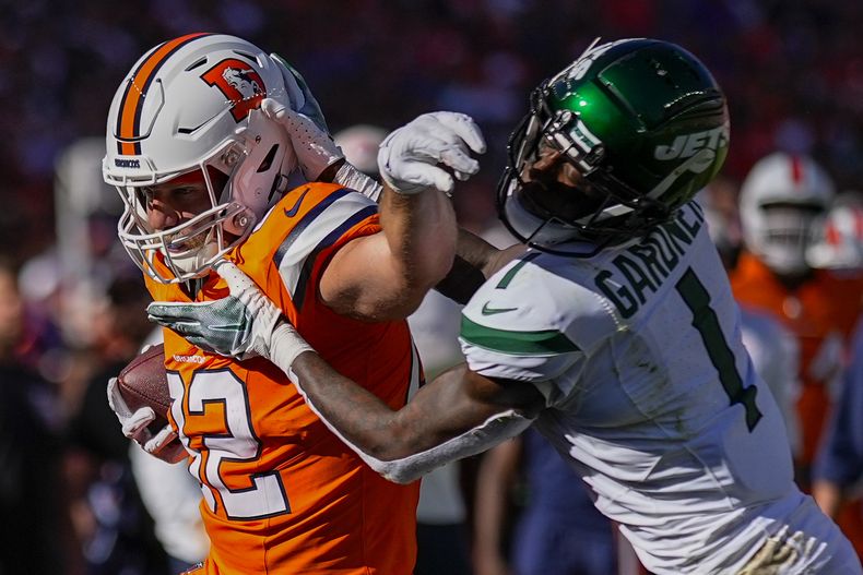 Adam Trautman, izquierda, ala cerrada de los Broncos de Denver, es sacado del campo por el cornerback de los Jets de Nueva York Sauce Gardner durante la primera mitad del juego de la NFL, el domingo 8 de octubre de 2023, en Denver. (AP Foto/Jack Dempsey)