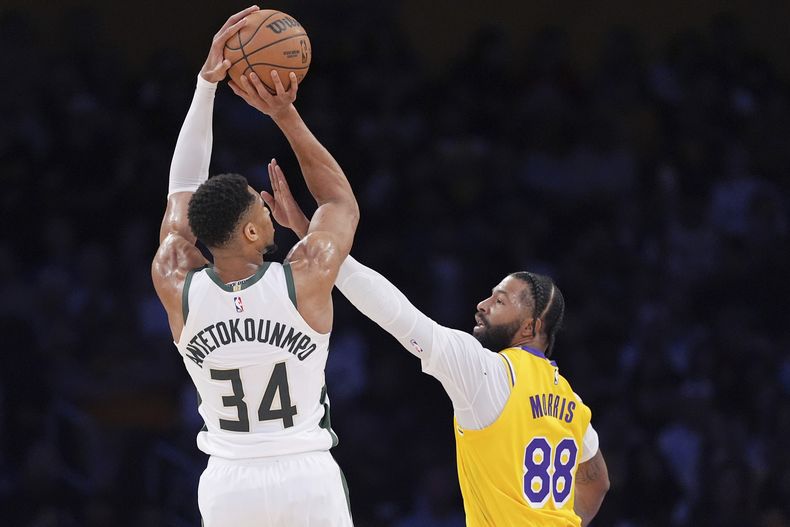 El alero de los Bucks de Milwaukee, Giannis Antetokounmpo, a la izquierda, dispara mientras el alero de los Lakers de Los Ángeles, Markieff Morris, defiende durante la primera mitad de un partido de baloncesto de la NBA, el jueves 20 de marzo de 2025, en Los Ángeles. (AP Foto/Mark J. Terrill)