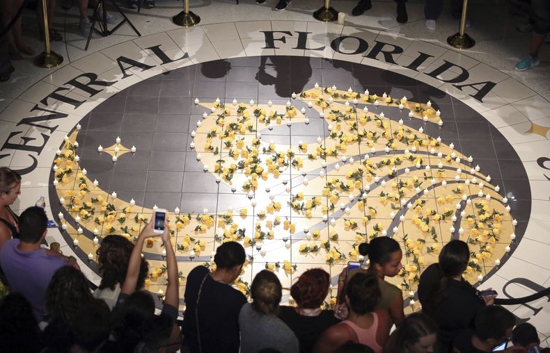 ARCHIVO - Estudiantes se reúnen en torno a velas encendidas en el logo de la Universidad Central de Florida, el 14 de junio de 2016. (Stephen M. Dowell/Orlando Sentinel via AP, archivo)
