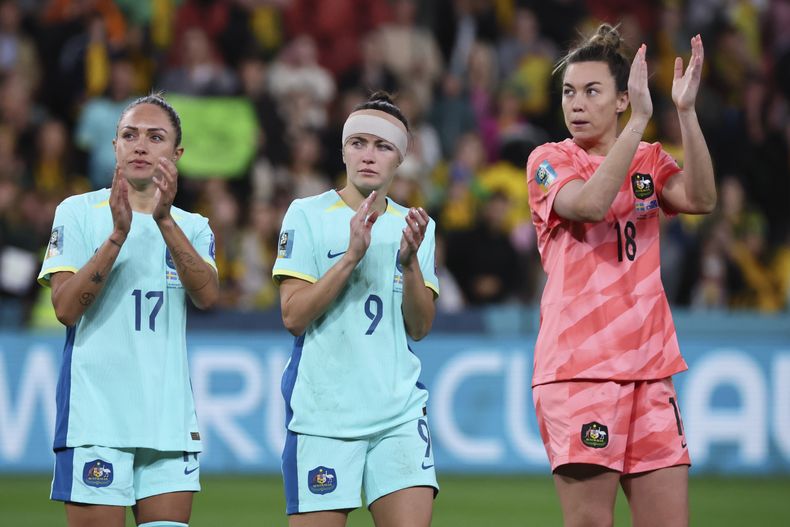 Las futbolistas australianas (de izquierda a derecha) Kyah Simon, Caitlin Foord y la guardameta Mackenzie Arnold saludan al público tras caer frente a Suecia en el partido por el tercer puesto del Mundial femenino, en Brisbane, Australia, el 19 de agosto de 2023. (AP Foto/Tertius Pickard)