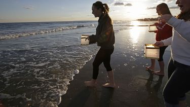americateve | Unas mujeres se acercan al mar para colocar linternas con mensajes escritos en ellas durante una ceremonia para conmemorar un a&ntilde;o de que la tormenta Sandy azot&oacute; Nueva York, el domingo 27 de octubre de 2013. El aniversario se cumple el 29 de