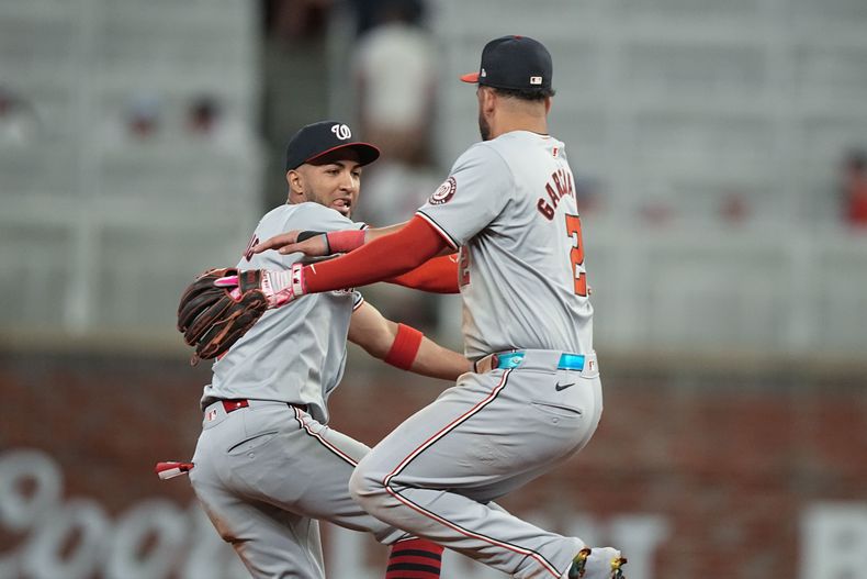 El jardinero de los Nacionales de Washington, Eddie Rosario (8), y el segunda base de los Nacionales de Washington, Luis García Jr. (2), celebran la victoria contra los Bravos de Atlanta, el miércoles 29 de mayo de 2024, en Atlanta. (AP Foto/Brynn Anderson)
