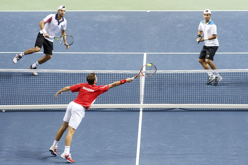 El jugador de Suiza, Stanislas Wawrinka, abajo, devuelve una pelota ante los italianos Simone Bolelli, izquierda, y Fabo Fognini, en el partido de dobles de su serie por las semifinales de la Copa Davis el s&aacute;bado, 13 de septiembre de 2014, en Gineb