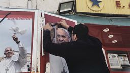 Un propietario de una tienda coloca un lazo negro sobre una foto del fallecido papa Francisco al conocer la noticia de su muerte a los 88 años, en Belén, Cisjordania, el lunes 21 de abril de 2025. (AP Foto/Mahmoud Illean)