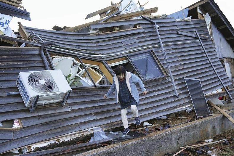 Una mujer camina entre las ruinas de su casa el viernes 5 de enero de 2024, en Wajima, prefectura de Ishikawa, Japón. (Kyodo News vía AP)
