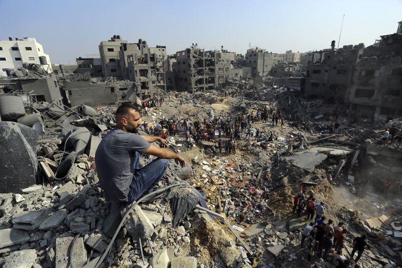 Un hombre se sienta sobre los escombros mientras otros buscan entre los restos de edificios atacados por la aviación israelí, en el campo de refugiados de Jabaliya, en el norte de la Franja de Gaza, el 1 de noviembre de 2023. (AP Foto/Abed Khaled)