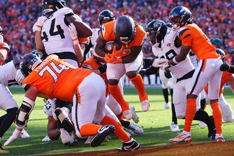 Jonah Coleman, centro, de los Broncos de Denver, brinca dentro de la zona de anotación para anotar un touchdown contra los Jaguars de Jacksonville en la segunda mitad del partido de la NFL, el domingo 20 de septiembre de 2026, en Denver. (AP Foto/David Zalubowski)