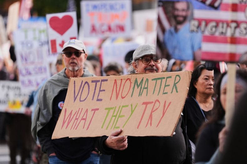 Una persona sostiene un cartel durante una marcha de protesta No Kings que anima a votar para las elecciones de noviembre en EEUU, el sábado 17 de octubre de 2026, en Seattle. (Foto AP/Lindsey Wasson)