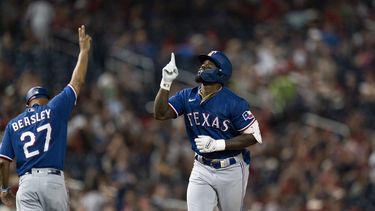 el jardinero derecho de los Rangers de Texas Adolis García celebra con el entrenador de tercera base Tony Beasley tras pegar un jonrón en la séptima entrada ante los Nacionales de Washington el viernes 7 de julio del 2023. (AP Foto/Stephanie Scarbrough)
