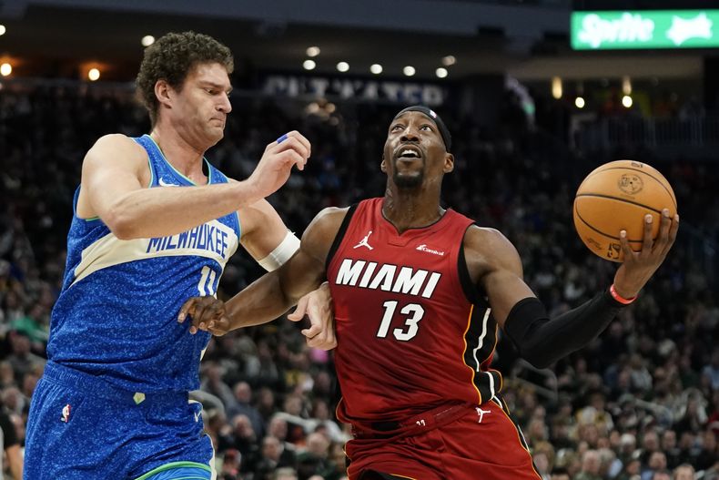 Bam Adebayo (13) del Heat de Miami conduce hacia el aro ante Brook Lopez de los Bucks de Milwaukee durante la 1ra mitad del juego de baloncesto de la NBA, el martes 13 de febrero de 2024. (AP Foto/Aaron Gash)