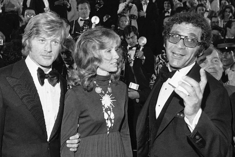 ARCHIVO - Robert Redford, de izquierda a derecha, su esposa Lola y el director Sydney Pollack aparecen en la presentación de la película Jeremiah Johnson durante el Festival de Cine de Cannes en Cannes, Francia, el 7 de mayo de 1972. (Foto AP/Jean-Jacques Levy, archivo)