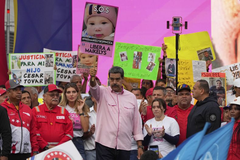 El presidente venezolano, Nicolás Maduro, con un cartel con la imagen de Maikelys Espinoza, una niña de dos años en custodia de Estados Unidos después de que sus padres fueran deportados de forma separada, en un acto por el Día de los Trabajadores en Caracas, Venezuela, el jueves 1 de mayo de 2025. (AP Foto/Ariana Cubillos)