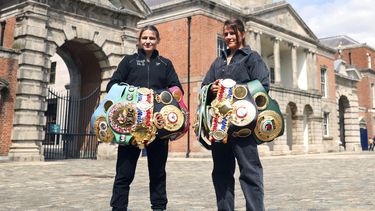 Katie Taylor (izquierda), monarca indiscutible de las ligeras y Chantelle Cameron, campeona indiscutible de las superligeras, posan frente al Castillo de Dublín, el jueves 18 de mayo de 2023 (AP Foto/Peter Morrison)